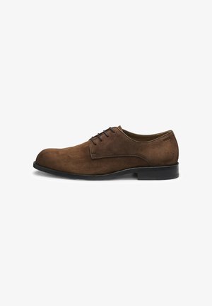 Zapato de vestir de hombre de ante marrón con cordones, suela negra, tacón bajo y costuras laterales sutiles sobre fondo blanco.
