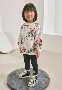 Sweatshirt blanc avec impression Minnie Mouse en noir et rose, associé à des leggings noirs et des baskets montantes noires avec des lacets blancs.