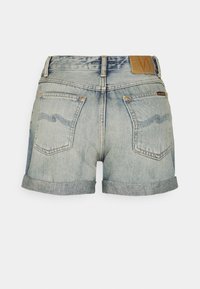 Jeansshorts i ljusblått, med uppvikta fållar, en etikett på midjan och två bakfickor med tydliga sömnadsmönster.