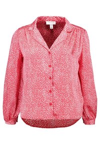 Blusa rossa con motivo a pois bianchi, maniche lunghe, apertura frontale con bottoni e colletto. Tessuto leggero, vestibilità ampia e orlo leggermente curvo.
