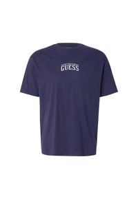 Camiseta de algodón de color azul marino con mangas cortas y escote redondo. Presenta texto en blanco que dice "ESTILO Y DISEÑO CLÁSICO GUESS" en el pecho.