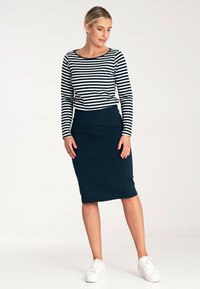 Pasiasty, długi rękaw top w kolorze granatowym i białym, zestawiony z dopasowaną granatową spódnicą. Obuwie to białe sneakersy, co tworzy casualowy zestaw.