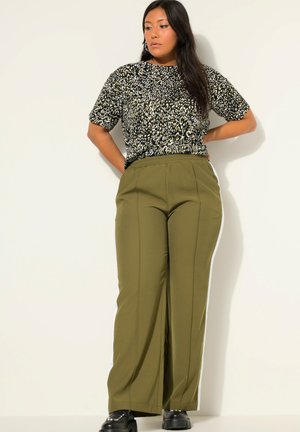 Korte mouw top met zwart en goud luipaardprint, gecombineerd met olijfgroene broek met wijde pijpen en witte zijstrepen, met een relaxte pasvorm.