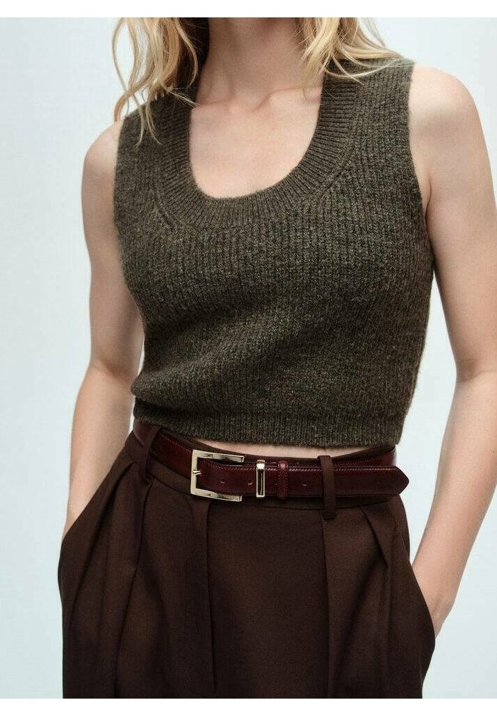 Femme portant un crop top en maille sans manches vert olive associé à un pantalon taille haute marron foncé et une ceinture marron foncé.