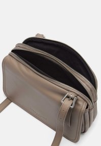 Szara skórzana torba na ramię z dwoma zamykanymi kieszeniami i płaskim paskiem. Widoczna jest gładka tekstura oraz subtelne detale przeszycia.