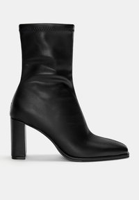 Bottine en cuir noir avec bout pointu, talon haut épais et partie supérieure froncée. Texture lisse et design minimaliste, sans éléments métalliques visibles.