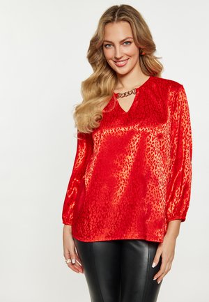 Rode satijnen blouse met een luipaardprint, driekwart mouwen en een sleutelgatdecolleté verfraaid met een gouden ketting. Gestructureerde en glanzende afwerking.