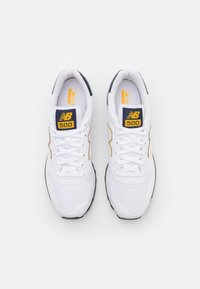 Baskets en mesh blanc et synthétique avec des accents bleu marine, logo doré et détails cousus. Design classique à lacets avec semelles extérieures en caoutchouc.