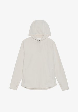 Lys beige hettegenser laget av mykt stoff, med halv glidelås foran, sidelommer og tommelhull i mansjettene, samt en rundet kant.