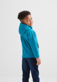 Turquoise hoodie with long sleeves and a hood, featuring a zip closure and side pockets. Worn with dark blue jeans.