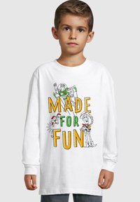 Valge pika varrukaga T-särk, millel on värviline graafiline tekst "MADE FOR FUN" ja koomiksikujutised Buzz Lightyearist, Woody'st ja väikestsest jänesest.