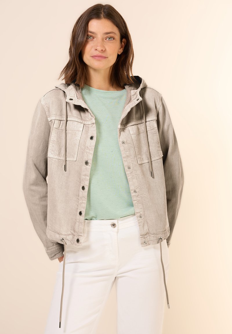 Light gray denim jacket with a hood, buttoned front, and two chest pockets. Worn over a mint green shirt and white pants. Smooth texture.