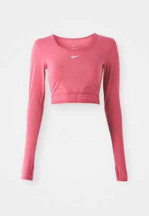 Hosszúujjú, rövid fazonú sportpóló egyszínű rózsaszínben, kerek dekoltázzsal. Anyaga sima, enyhe fényes hatású; az alján "NIKE PRO" felirattal.