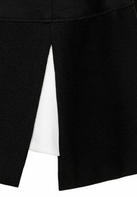 Detalle de tela negra texturizada con una hendidura triangular que revela una tela blanca suave debajo.