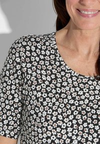 Schwarzes Blumenoberteil mit Rundhalsausschnitt, kurzen Ärmeln und einem Muster aus kleinen weißen Blumen mit braunen Akzenten auf einem dunklen Hintergrund.