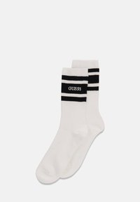 White socks with a ribbed texture, featuring two black stripes and the "GUESS" logo in black on the cuff. Standard crew length.