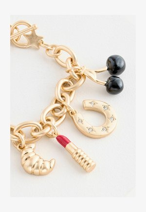 Kuldmetallist võlu käevõru, millel on musta kirsiga, croissanti, huulepulga ja hobuseshoe võlud, millel on teemantaktsendid ja tekstureeritud viimistlus.