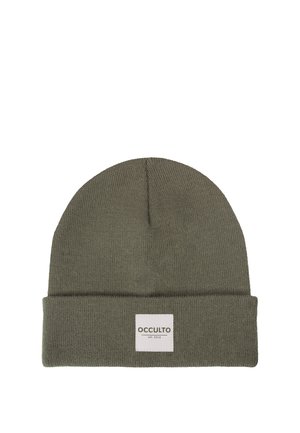 Junge Person passt grüne Beanie mit „OCCULTO“-Label an, trägt einen orangen Zip-up-Pullover vor einfachem weißem Hintergrund.