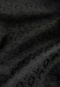 Tessuto nero testurizzato con un motivo sottile di forme geometriche. Il materiale appare tessuto, creando un aspetto ricco e stratificato.