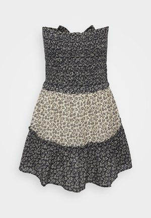 Robe à motif floral avec un corsage smocké. Caractéristiques d'un design à volants, de couleurs marine foncé et crème, et d'un ourlet à volants.