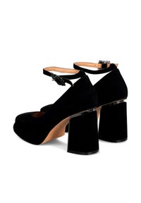 Scarpe eleganti in suede nero con punta chiusa e cinghietto alla caviglia, dotate di tacchi quadrati spessi con un accento specchiato. Texture liscia.