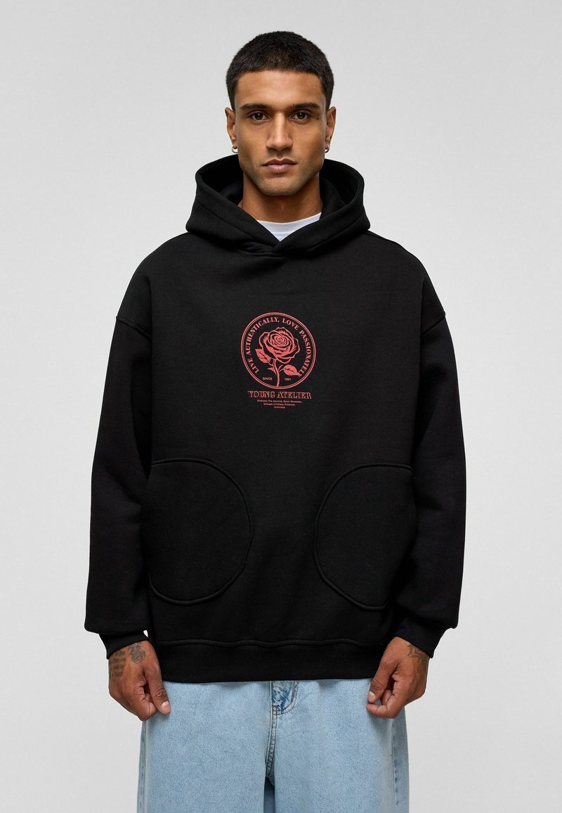Zwart hoodie met twee grote voorzakken, voorzien van een rode rozenafbeelding en tekst. Gemaakt van zachte stof met een ontspannen pasvorm.