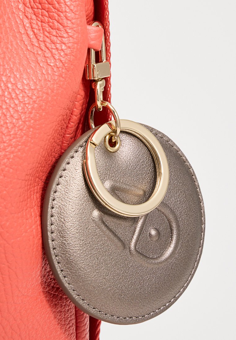 Borsa in pelle corallo con finitura tessurizzata, dotata di una chiusura in metallo dorato e un portachiavi rotondo in metallo attaccato. Il portachiavi presenta un dettaglio con logo.