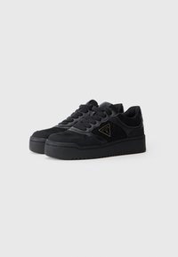 Baskets noires présentant un mélange de matériaux lisses et texturés, avec une semelle en caoutchouc solide et un accent logo en forme de triangle.