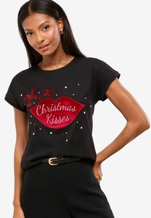 Must märgiga T-särk, millel on punane villane huulegraafika ja valge tekst "Jõulukallistused", kaunistatud väikeste valgete punktide ja punaste paelte aktsentidega.