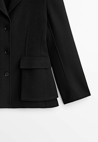 Blazer en mélange de laine noire avec une coupe ajustée, un design à simple boutonnage, cinq boutons noirs et une poche à rabat à l'avant.