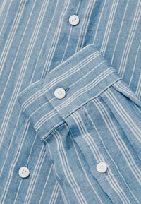 Lichtblauw gestreept shirt met witte strepen. Voorzien van een knoopmanchet en witte knopen. Gemaakt van een gestructureerde stof, ideaal voor casual kleding.
