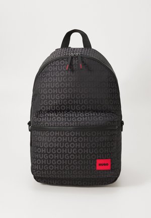 Black backpack featuring repeated "HUGO" logo pattern, two zippered compartments, and a red branded patch on the front.