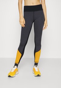 Leggings atléticos de cintura alta con un cuerpo gris oscuro, paneles laterales negros y secciones de acento amarillas; textura suave, diseñados para la comodidad.