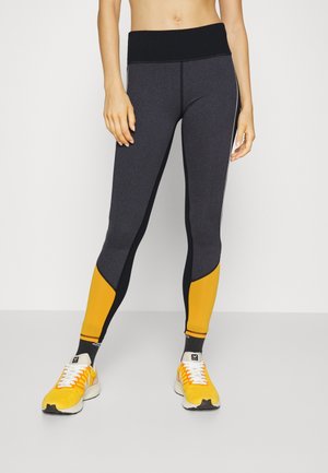 Legging de sport taille haute avec un corps gris foncé, des panneaux latéraux noirs et des sections accentuées jaunes ; texture lisse, conçu pour le confort.