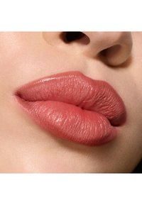 Primo piano di labbra che mostrano una texture morbida e umida in una tonalità rosa nudo naturale. Definizione sottile con una finitura liscia e lucida.