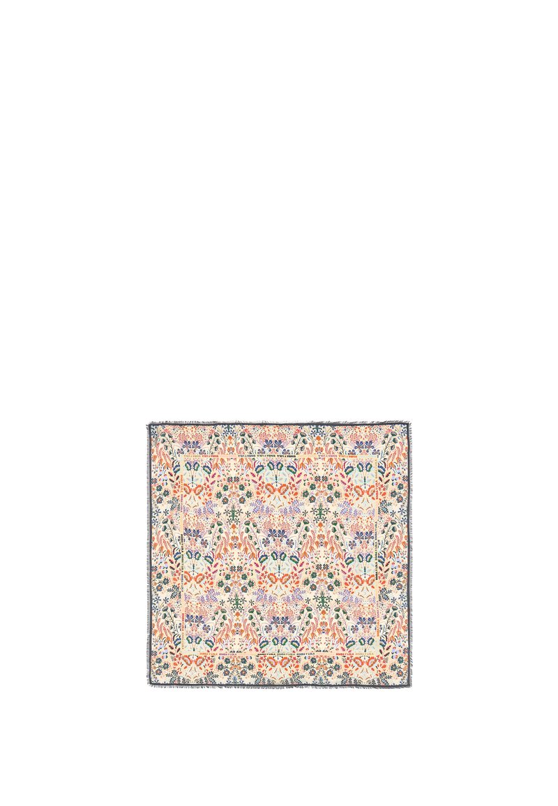 Bufanda con estampado floral en tejido suave con fondo crema, presenta flores coloridas y toques verdes, terminada con bordes deshilachados.