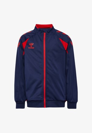 Marineblå sportsjakke med rød lynlås, røde skulderdetaljer og et rødt hummel-logo på venstre bryst.