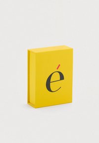 Κίτρινο ορθογώνιο κουτί με ένα μαύρο πεζό γράμμα «é» και μια κόκκινη προφορά πάνω από το γράμμα. Ομαλή εξωτερική επιφάνεια με συμπαγή, μινιμαλιστικό σχεδιασμό.