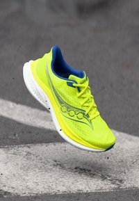 Bright yellow running shoe with a lightweight mesh upper, blue accents, and white sole. Features a textured surface and curved design elements.