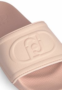 Infradito rosa chiaro con una fascetta testurizzata che presenta un logo in rilievo. Sole interno liscio e bordo leggermente rialzato.
