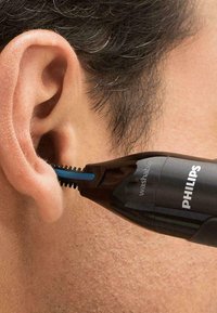 Philips ear trimmer, black with blue accents, featuring a washable head and fine bristles, positioned near an ear.
