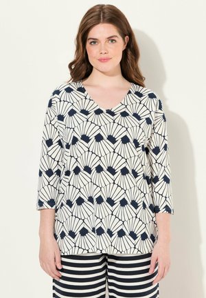 V-pääntieblouse, jossa on kolme neljännestä hihaa, navy- ja valkoiset simpukkakuviot vaalealla taustalla, valmistettu pehmeästä, kevyestä kankaasta.