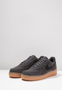 Černé plátěné tenisky s gumovou podrážkou, se šedými tkaničkami, černým logem Nike a zaoblenou špičkou.