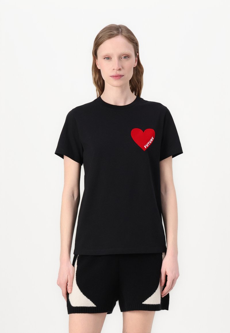T-shirt en coton noir à manches courtes, avec un graphique en forme de cœur rouge et le mot "FUTURE" à l'intérieur du cœur, porté avec un short noir.