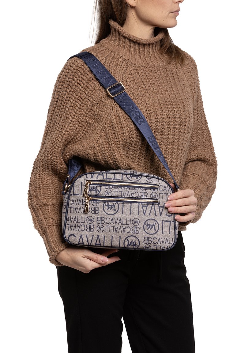 Borsa a tracolla blu e beige con stampa del logo, due tasche con zip e una tracolla robusta. Il tessuto ha una texture liscia.