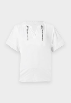 Top blanco de manga corta con escote en V y cordones retorcidos en blanco y negro que cuelgan de ojetes metálicos en el escote.