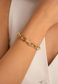 Bracciale in oro con maglie colorate in rosso, blu e rosa, che presenta una texture liscia e un design ad incastro.