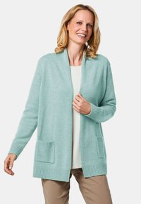 Hellmintgrüner Cardigan mit offenem Vorderteil, gerippten Bündchen und zwei aufgesetzten Taschen vorne. Weiche Textur, lässiges Design.