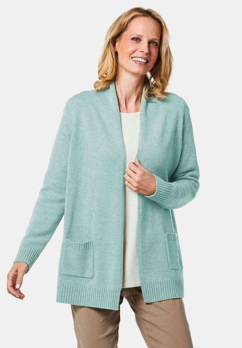 Hellmintgrüner Cardigan mit offenem Vorderteil, gerippten Bündchen und zwei aufgesetzten Taschen vorne. Weiche Textur, lässiges Design.