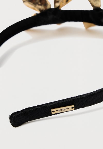Černá textilní čelenka s texturovaným povrchem a kovovými zlatými doplňky s logem. Květinový motiv nahoře.